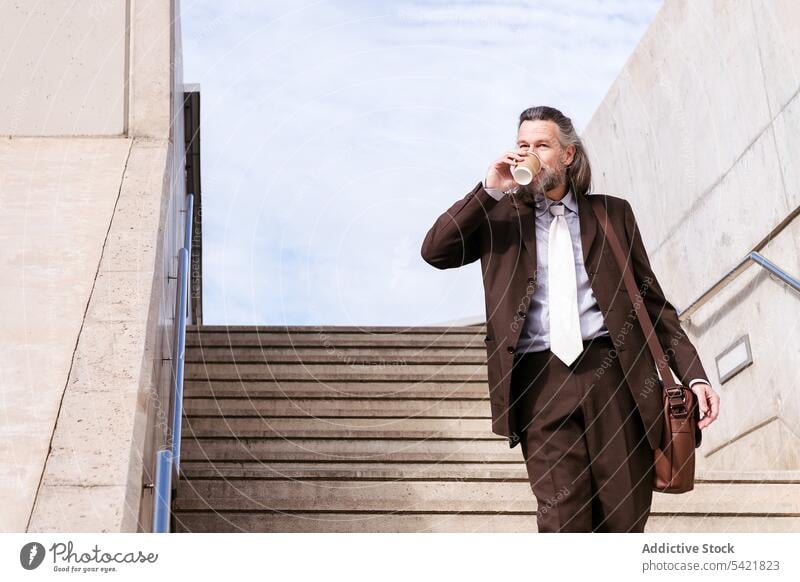 Stilvoller Geschäftsmann mit Kaffee zum Mitnehmen auf einer Treppe in der Stadt Imbissbude Schritt stilvoll selbstbewusst elegant trinken Mann Lebensmitte reif