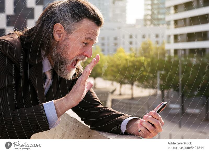 Glücklicher bärtiger Geschäftsmann bei einem Videoanruf auf einem Mobiltelefon in der Stadt Smartphone reden urban Lächeln Telefon Kommunizieren Vollbart Stil