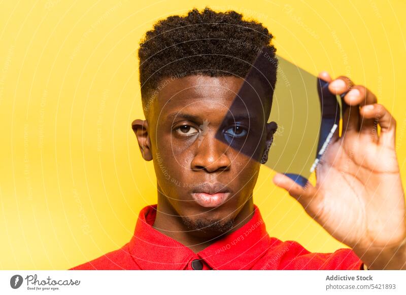 Schwarzer Mann schaut durch Lichtfilter in die Kamera Filter Farbe Stil Atelier Model ernst hell trendy männlich ethnisch schwarz Afroamerikaner lebhaft