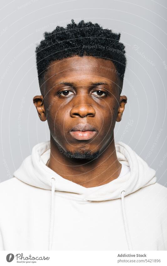 Seriöser schwarzer Mann mit weißem Kapuzenpulli ernst selbstbewusst Afro-Look Porträt Menschliches Gesicht Starrer Blick männlich jung Afroamerikaner starren