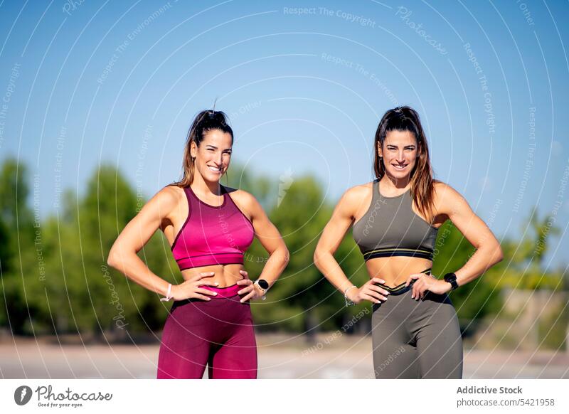 Fröhliche sportliche Zwillinge auf Asphalt stehend Frauen passen Schwester Zusammensein heiter positiv Aktivität Lifestyle Lächeln Fitness Inhalt Optimist froh
