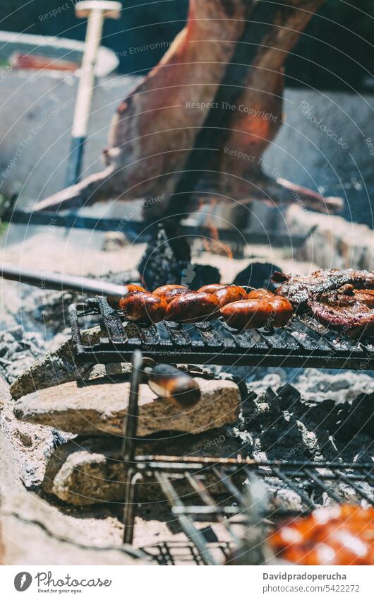 Lamm im Grill gebraten Barbecue gegrillt Rippen Fleisch Tier hacken Holzkohle chourizo Kohle Lebensmittel grillen Essen zubereiten Küche Glut kleben Sommer