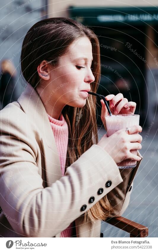 Porträt einer schönen kaukasischen Frau auf einer Terrasse, die einen Smoothie trinkt. urbanes und Lifestyle-Konzept abschließen Café Croissant Frühstück