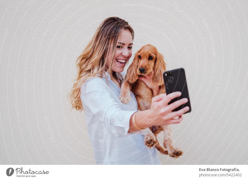 Junge Frau auf der Straße mit ihrem Cockerhund beim Fotografieren mit dem Mobiltelefon. Lifestyle im Freien mit Haustieren Handy Technik & Technologie Selfie