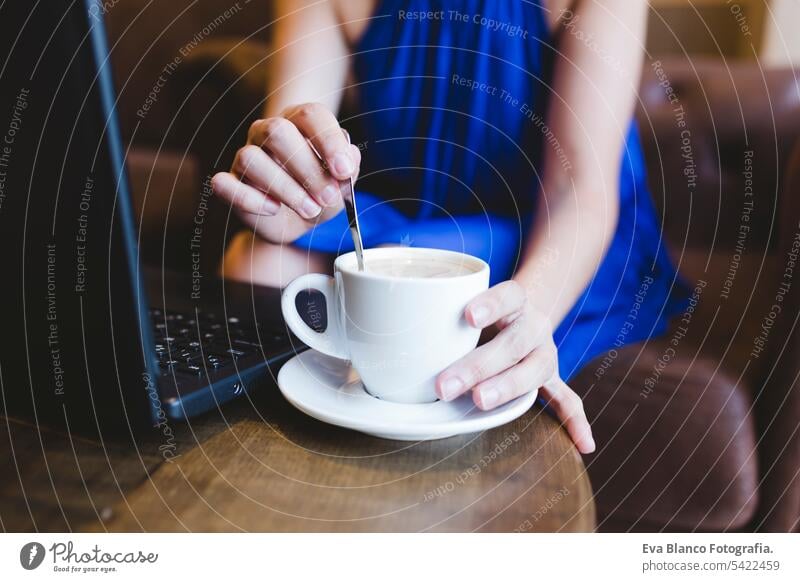 Draufsicht auf eine junge schöne Frau, die am Laptop schreibt, daneben Kaffee. Lässiges blaues Kleid. Modernes Leben im Innenbereich Hipster Hochschule Computer