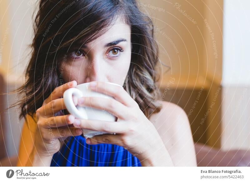 junge schöne Frau genießt eine Tasse Kaffee in einem Café. Laptop neben. Lässiges blaues Kleid. Modernes Leben im Innenbereich Morgen Beteiligung Schönheit