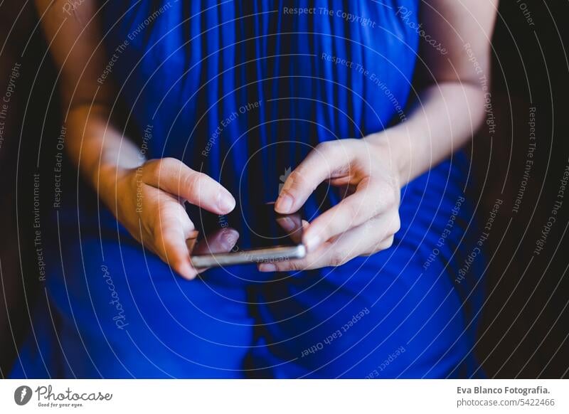 Draufsicht auf eine junge Frau, die ein Mobiltelefon benutzt und ein lässiges blaues Kleid trägt. Innenräume, Technologie und Lebensstil Hipster stylisch