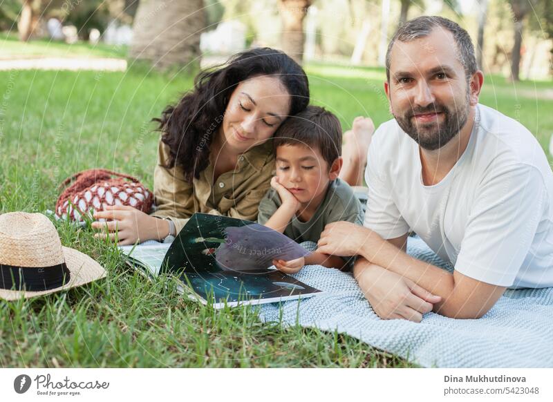 glückliche Familie lächelnd mit einem Sohn lesen ein Buch zusammen im Park im Freien im Sommer Mama Papa Vater Mutter Elternschaft Vaterschaft Mutterschaft