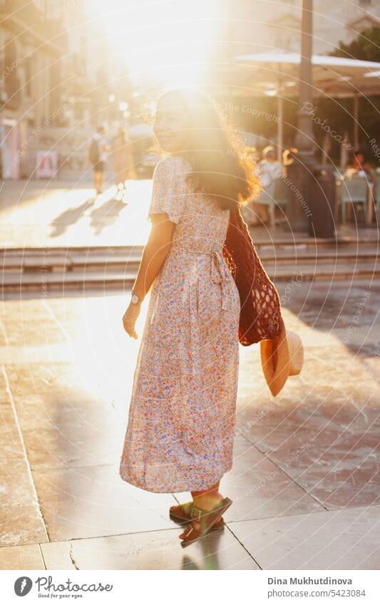 schöne brünette Frau Tourist in europäischen Stadt lächelnd bei Sonnenuntergang im Sommer, zu Fuß auf der Straße. Weibliche Solo-Reisende schaut in die Kamera in Valencia, Spanien.