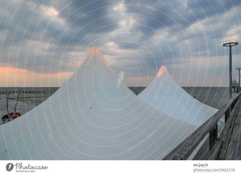 Alpenglühen - beleuchtete Spitzen zweier Zelte am Strand dicht bei der Seebrücke Zeltspitze Himmel Wolken Gewitterwolken Meer Ostsee Horizont Wetter Zingst