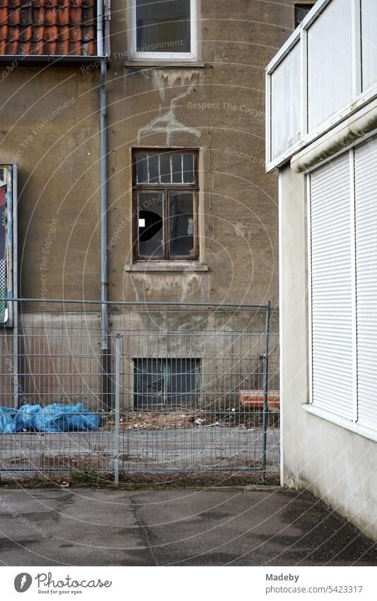 Hinterhof im Gewerbegebiet mit heruntergekommenen Fassade eines Abbruchhaus mit kaputter Fensterscheibe in Naturfarbenin Detmold am Teutoburger Wald in Ostwestfalen-Lippe