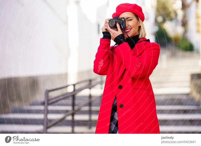 Elegante Frau, die ein Foto auf der Straße mit roter Kleidung macht. Fotoapparat Fotograf fotografieren Fotografie Hobby Gebäude Stil Mode Design feminin