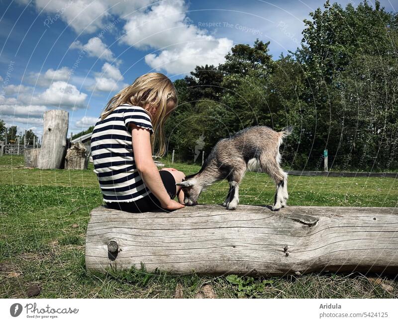 Vorsichtige Annäherung | Kind und kleines Zicklein auf einem Baumstamm Mädchen Ziege Tier Streichelgehege Nutztier Tierjunges Außenaufnahme Natur fressen
