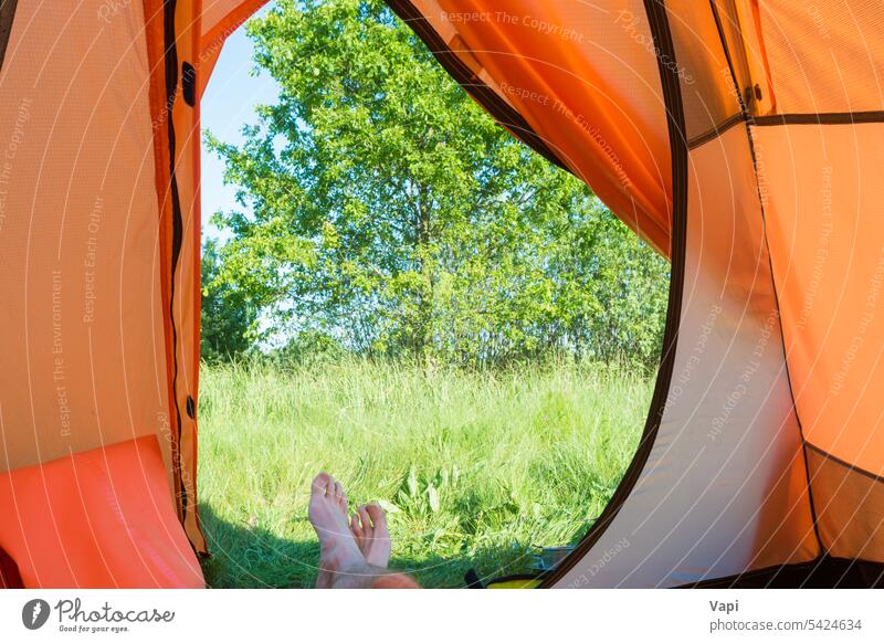 Mann ruht sich im orangefarbenen Zelt aus Lager Urlaub Camping Beine Natur im Inneren Ansicht Gras Fuß Menschen ruhen Erholung Wald Baum Landschaft Abenteuer
