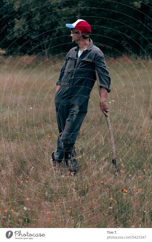 Farmer farmers Mann Heugabel steht Farbfoto aufgestützt Wiese basecap Außenaufnahme Tag Mensch Erwachsene overall