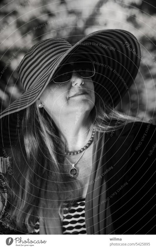 Bildnis einer mondänen Frau mit großem Hut, Sonnenbrille und reichlich Schmuck Dame langhaarig reife Frau elegant feminin Porträt Lifestyle Lady reich und schön