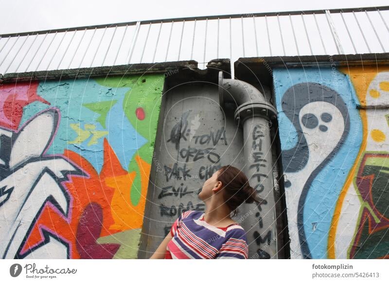 junge Frau blickt an eine Graffiti-Wand Mauer Jugendliche Mensch bunt graffity Graffitis Fassade Schriftzeichen Zeichen Kunst Kreativität Subkultur Straßenkunst