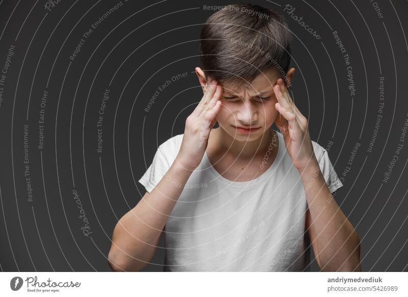 Handsome Teenager Junge trägt lässig weißes T-Shirt stehend über isolierten Hintergrund leiden unter Kopfschmerzen verzweifelt und gestresst, weil Schmerzen und Migräne. Hände auf dem Kopf.