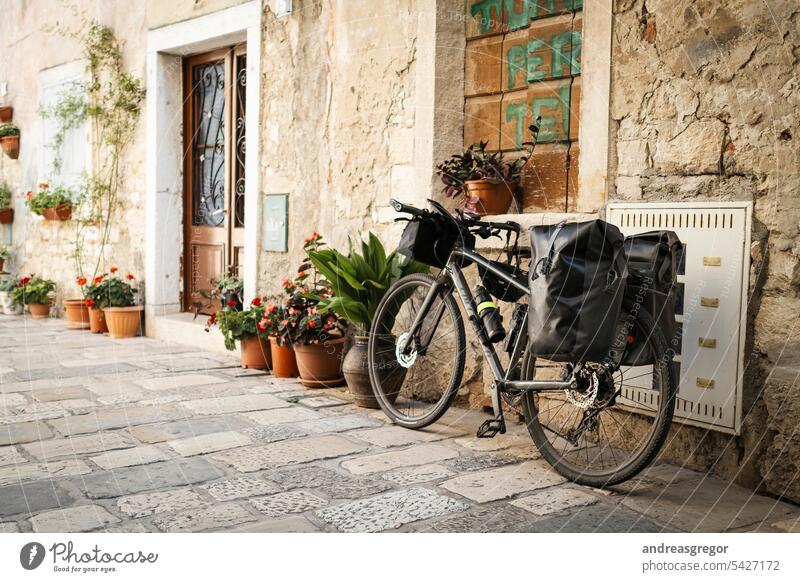 Fahrrad mit bepackten Taschen in einer malerischen Gasse in einem südeuropäischen Ort Fahrradreise Fahrradtour Fahrradfahren Bikepacking Urlaub Südeuropäisch