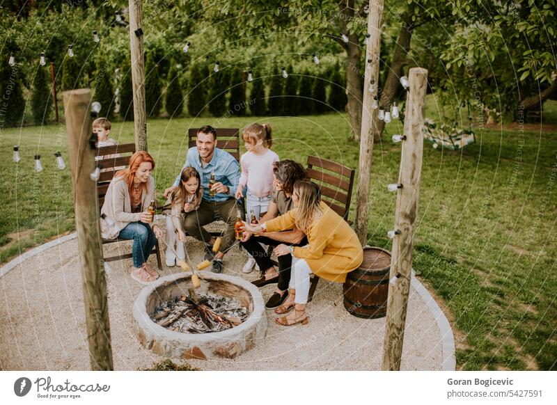 Freunde, die sich amüsieren und im Hinterhof des Hauses Maiskolben backen Erwachsener Barbecue grillen lässig Kaukasier Holzkohlegrill heiter Nahaufnahme lecker