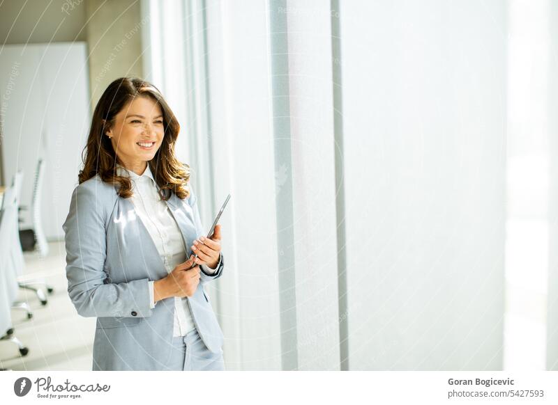 Junge Frau arbeitet am digitalen Tablet am Bürofenster Erwachsener allein attraktiv schön Schönheit hell brünett Business Geschäftsperson Geschäftsleute