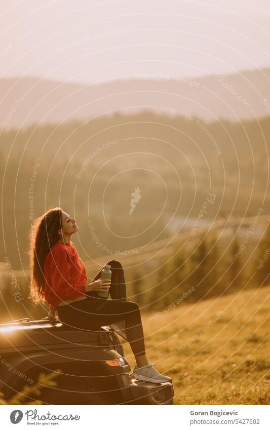 Junge Frau entspannt sich auf der Motorhaube eines Geländewagens auf dem Lande Erwachsener Abenteuer attraktiv Auto Automobil schön Pause Windstille PKW