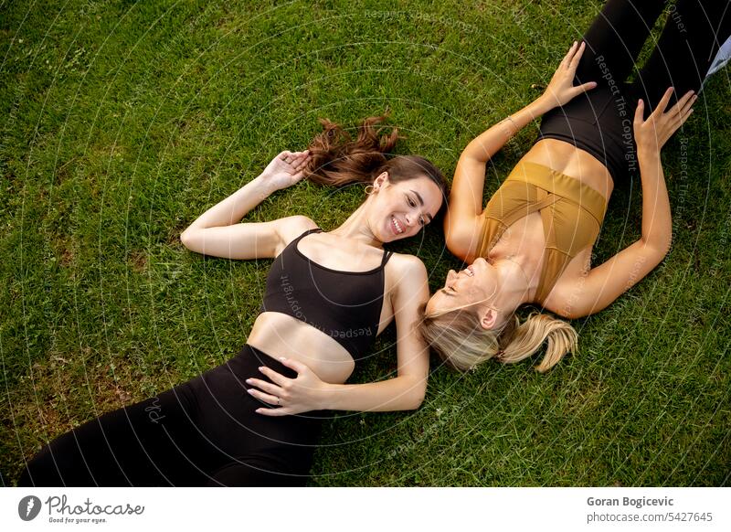 Zwei hübsche junge Frauen liegen im Gras Freundschaft Kaukasier zwei Menschen Gesicht Erwachsener Paar niedlich Behaarung lässig Park Zusammensein grün