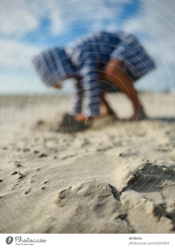Sand am Strand, im Hintergrund spielt ein Kind in gestreiftem Bademantel Spielen Unschärfe Sommer Meer Ferien & Urlaub & Reisen Küste Sommerurlaub Sandstrand