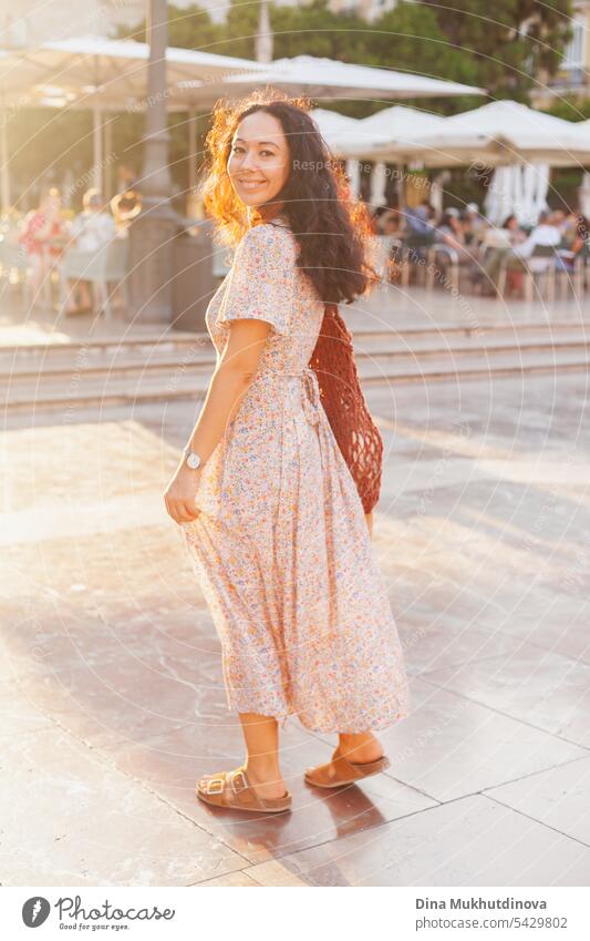 Schöne Touristin bei Sonnenuntergang in Valencia, Spanien. Brunette Frau Sommerkleid mit trendigen Häkeltasche zu Fuß die Straße. schön traumhaft Tourismus