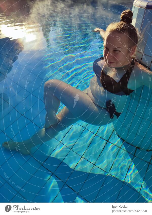 Porträt einer lächelnden jungen Frau, die sich im beheizten Schwimmbad entspannt Sonnenlicht Vergnügen Erholung Wellness Sommer Morgenlicht Freizeit & Hobby