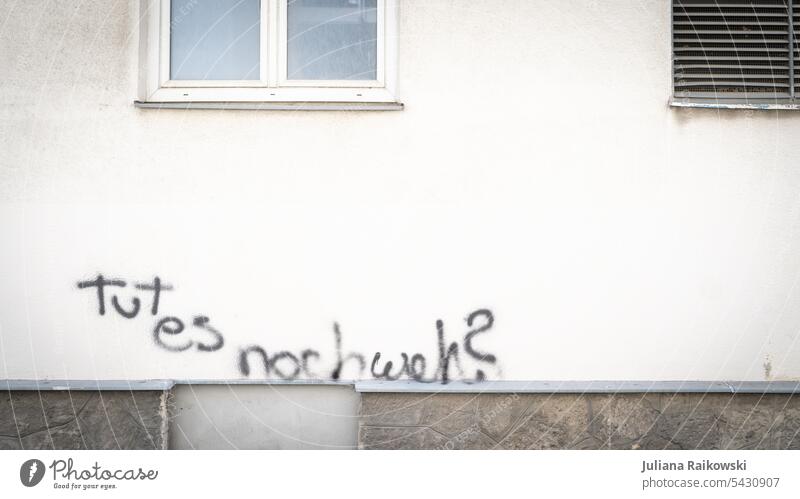 Graffiti mit Inschrift „Tut es noch weh?“ Wand Mauer Schriftzeichen Fassade Außenaufnahme Farbfoto Menschenleer Tag Stadt Zeichen Haus Textfreiraum oben
