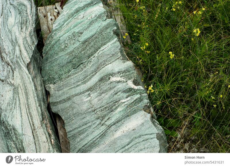 Gestein mit türkisfarbenen Schichten in einer Wiese gelagert Steinbrocken Geologie unbearbeitet Steinbearbeitung Berge u. Gebirge Linien Struktur Gesteinskunde