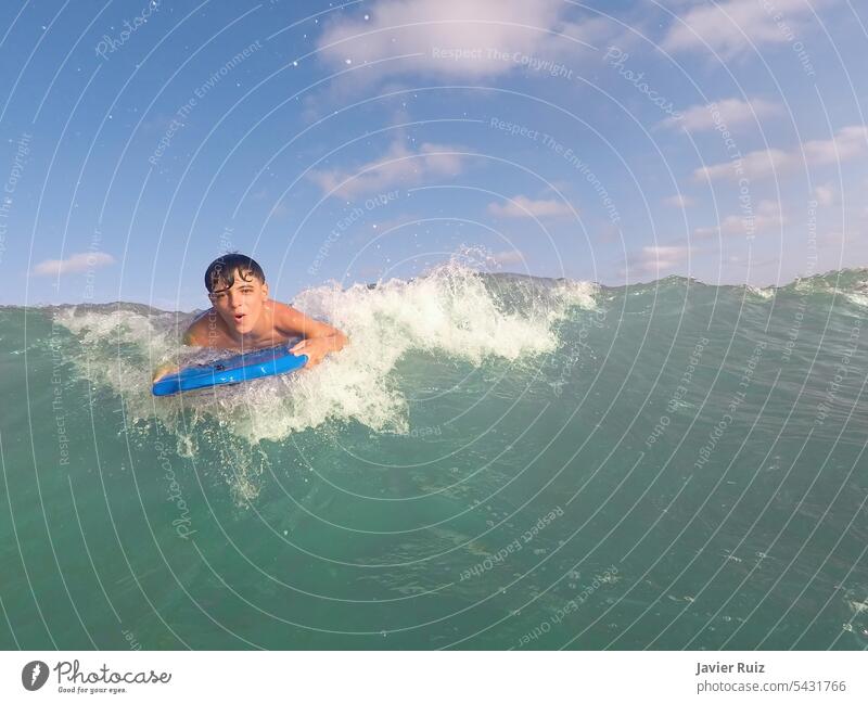 Junge Bodyboarding eine Welle auf einem türkisfarbenen Wasser Strand an einem sonnigen Sommertag, bodysurfing, Spaß am Strand, Kopie Raum Brandung Surfen winken