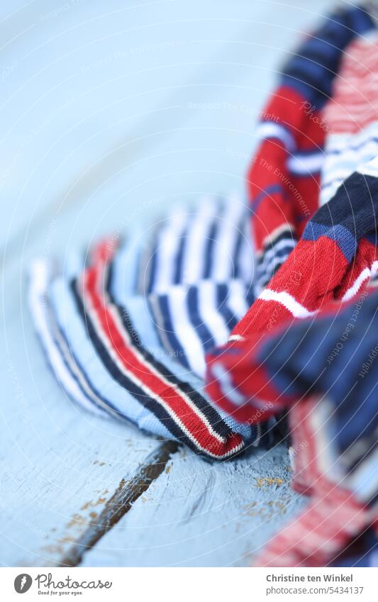 rot-weiß-blau gestreifter Stoff auf hellblauem Holz rot weiß blau Streifen maritim Muster Holzuntergrund Außenaufnahme rustikal Sommer Textilien textil Material
