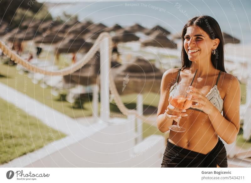 Lächelnde junge Frau im Bikini, die ihren Urlaub am Strand genießt trinken Italien Stroh Seeküste Erwachsener Bekleidung Fröhlichkeit Feiertag