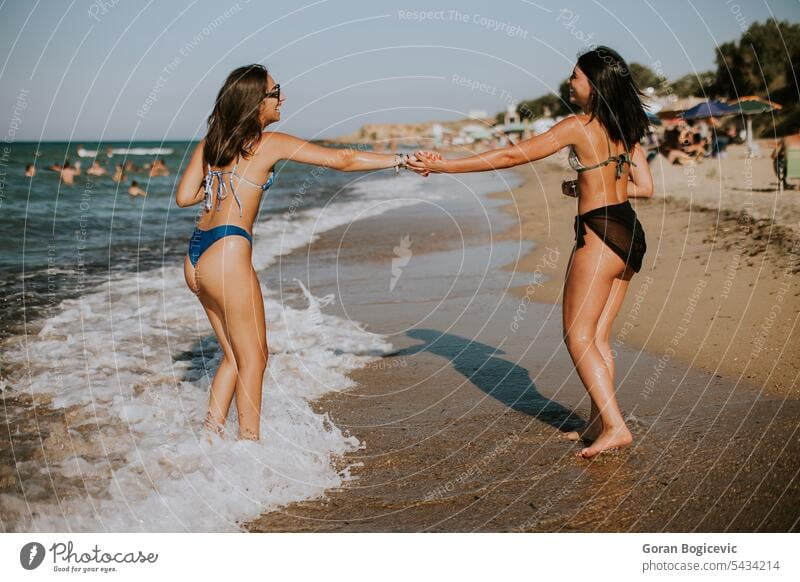 Zwei hübsche junge Frauen haben Spaß am Meer Sommer Bikini Freunde Strand Urlaub Badebekleidung MEER Zusammensein Menschen Fröhlichkeit Sand Glück Wasser heiter