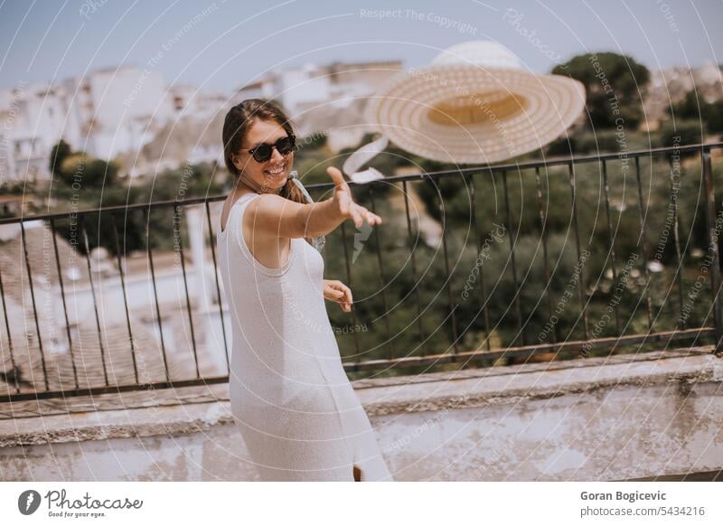 Eine junge Frau in einem weißen Kleid wirft einen Hut während eines Touristenbesuchs in Alborebello, Italien alborebello Italienisch werfen Werfen schön Mädchen