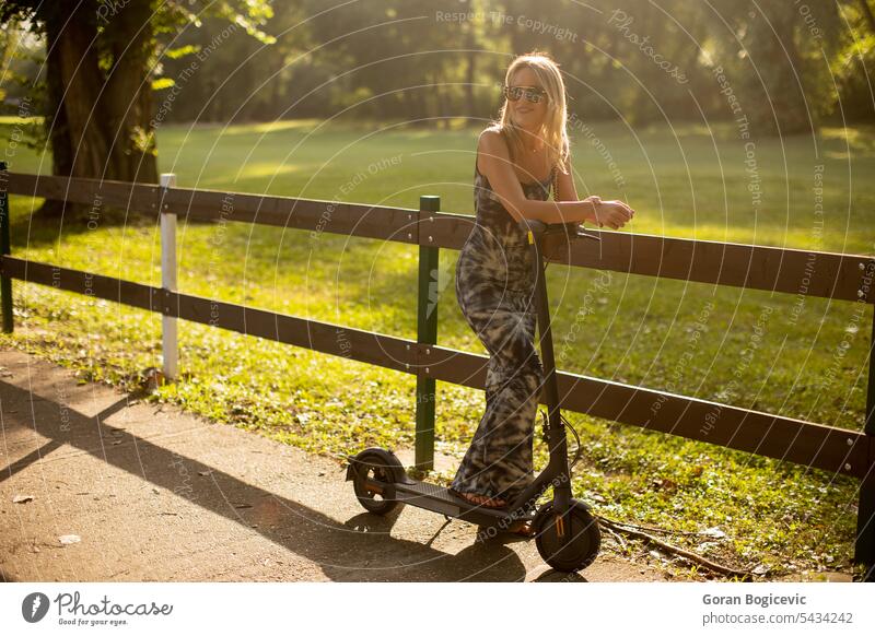 Junge Frau mit einem Elektroroller im Park an einem sonnigen Sommertag aktiv Aktivität attraktiv schön lässig Kaukasier Großstadt Tag Öko elektrisch Spaß