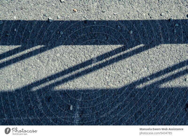 Senkrechter Blick auf den Boden auf den Schatten eines Geländers schatten schattenwurf straße verkehr bahnübergang schranke grenze kontrast kontrastreich linien