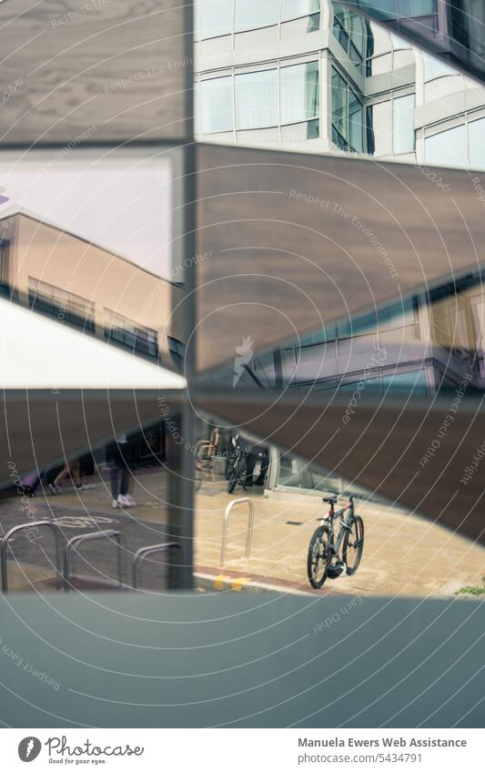 In der Fassade eines Gebäudes spiegeln sich Fahrräder, Straße und Gebäude abstrakt spiegelung fahrrad verkehr gebäude geteilt verschachtelt getrennt kontrast