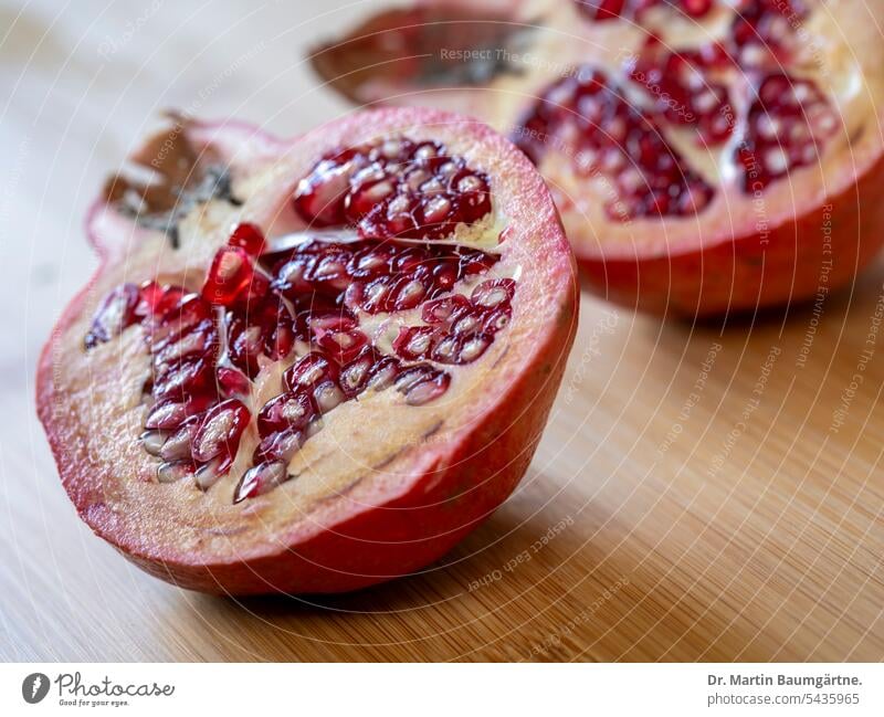 Ein Granatapfel, halbiert mit Samen und rotem Samenmantel (Arillus); Mittelformataufnahme Frucht Obst Beere Alte Kulturpflanze Nahaufnahme geringe Tiefenschärfe