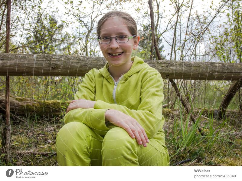 Ein fröhliches grünes Grundschulmädchen lernt begeistert etwas Neues über Natur und Umwelt Mädchen Kind lachen klein grasgrün Frühling Wald Ökologie draußen