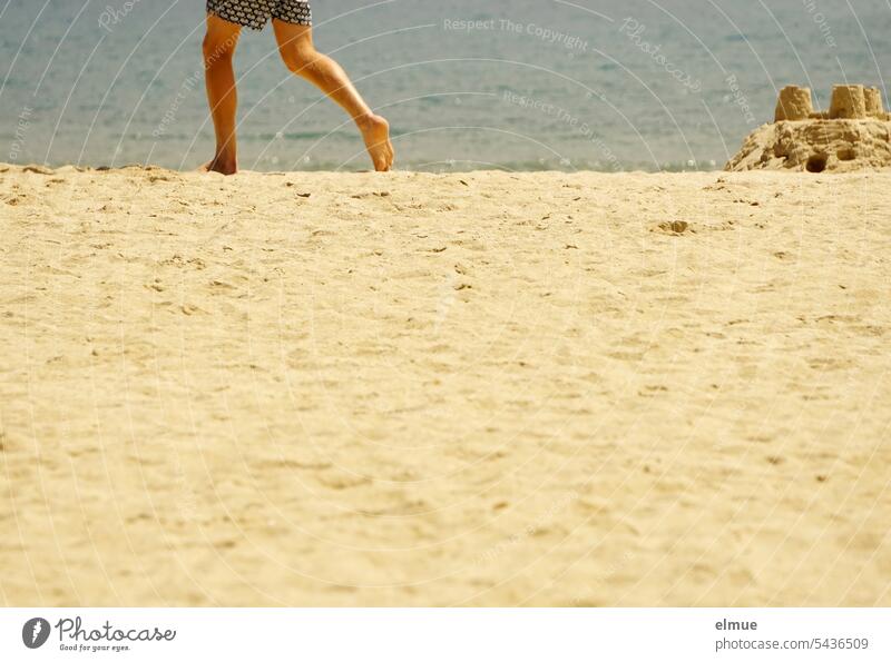 Teil einer Sandburg am weißen Strand vor blauem Meer und die Beine einer davonlaufenden Person Wasser Mittelmeer Elba Italien Sommer Blog Thyrrenisches Meer