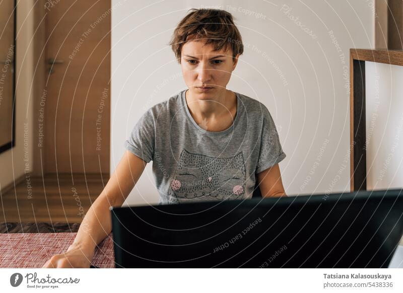 Eine Frau in Hauskleidung arbeitet zu Hause an Laptops mit angespanntem Blick Netzwerk online Anschluss Lebensstile Heimarbeitsplatz Fernarbeit häusliches Leben