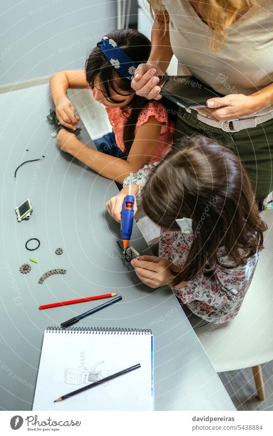 Schüler arbeiten mit Maschinenteilen neben dem Lehrer im Robotikunterricht unkenntlich Kinder Frau Spielfigur elektronisch Schaltkreis elektrisch Roboter
