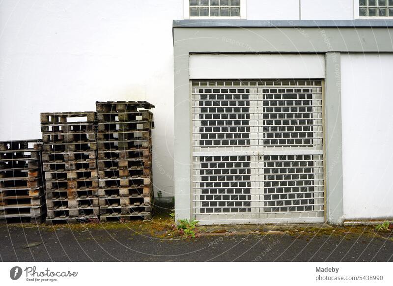 Gestapelte Europaletten aus Holz vor einem weißen Gebäude mit vergitterter Tür auf dem Hof eines Winzer in Traben-Trarbach an der Mosel im Kreis Bernkastel-Wittlich in Rheinland-Pfalz