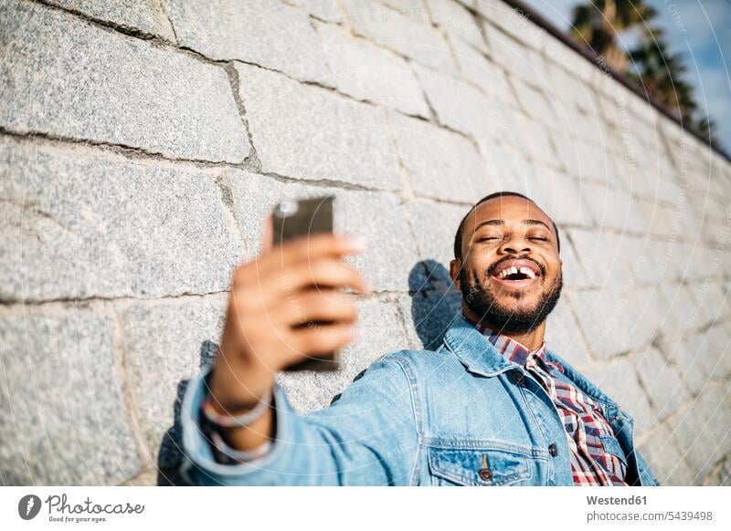 Porträt eines lachenden jungen Mannes, der ein Selfie mit seinem Mobiltelefon macht Selfies Männer männlich Erwachsener erwachsen Mensch Menschen Leute People