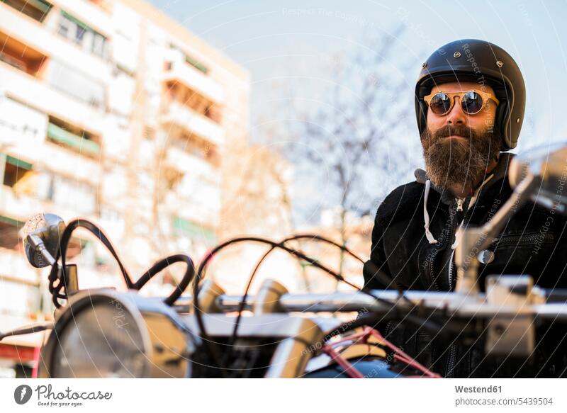 Porträt eines bärtigen Motorradfahrers mit Helm und Sonnenbrille auf seinem Motorrad sitzend Mensch Menschen Leute People Personen Mann Männer männlich