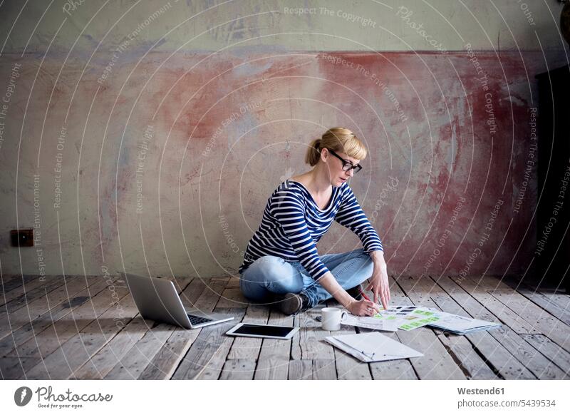 Frau sitzt auf Holzboden in einem unrenovierten Zimmer eines Dachgeschosses und arbeitet weiblich Frauen Loft Lofts Erwachsener erwachsen Mensch Menschen Leute