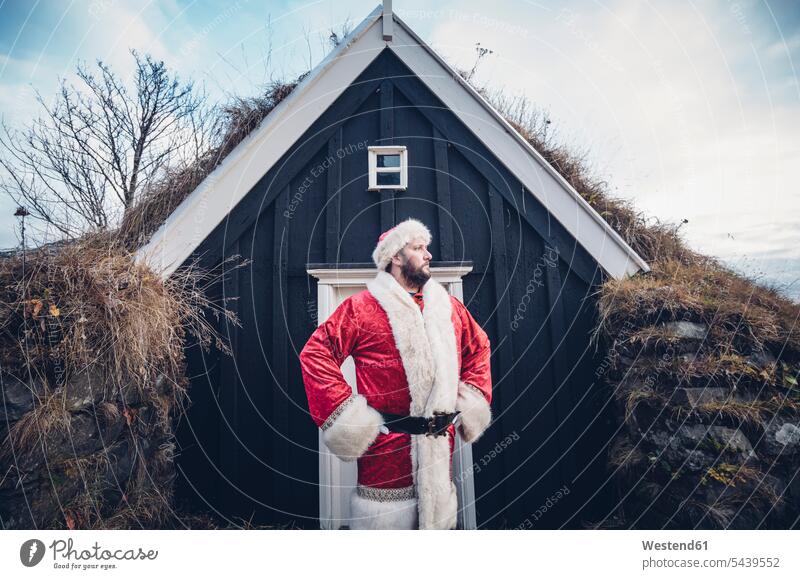 Island, Weihnachtsmann vor Hütte stehend mit Blick in die Ferne Blockhütte Blockhütten steht Weihnachtsmänner Weihnachtsmaenner Santa Claus Nikolaus Weihnachten